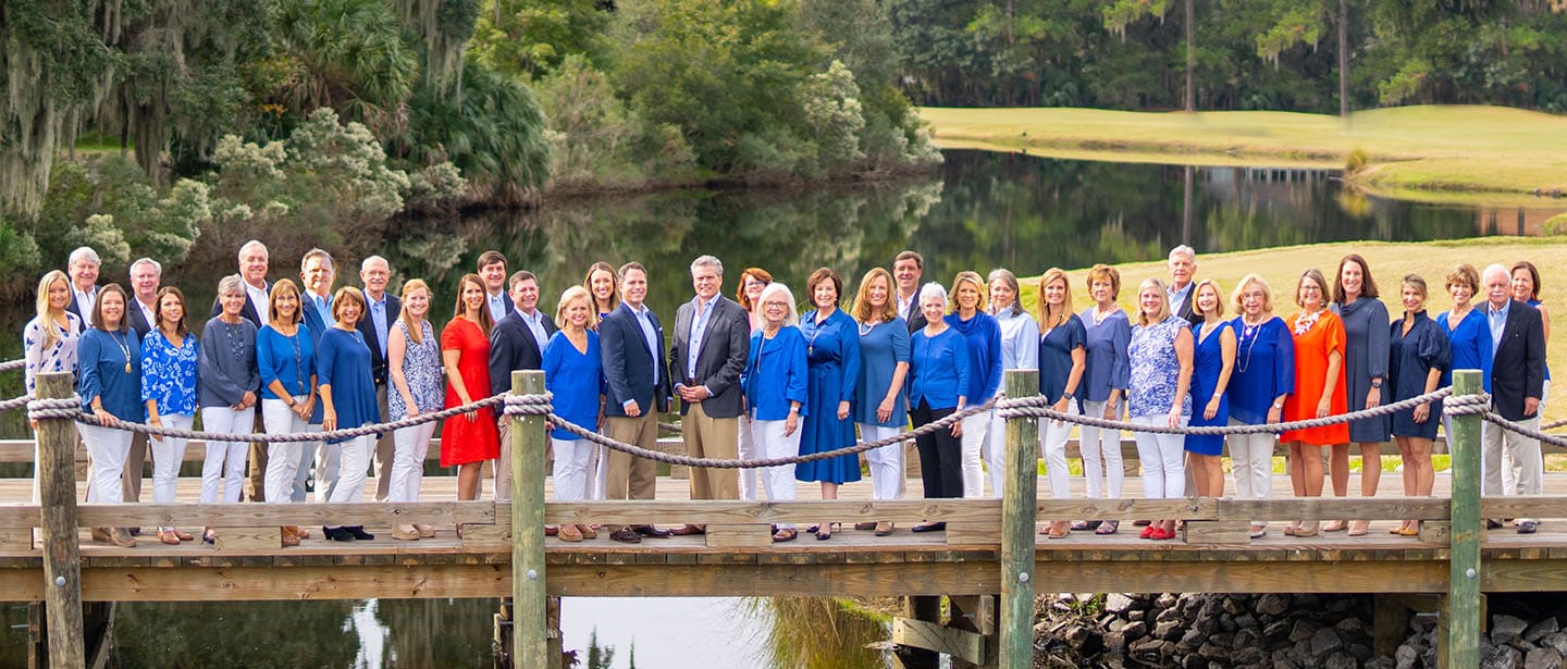 The real estate team, many of them wearing red, white and blue stand on a bridge for a recent photo opportunity.