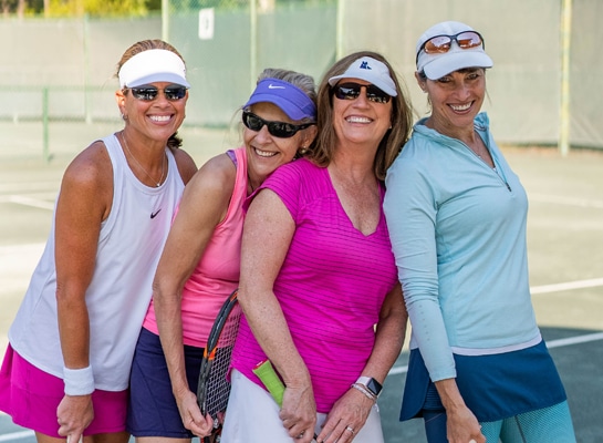 Four female friends connect on the pickleball courts for an afternoon of smiles.