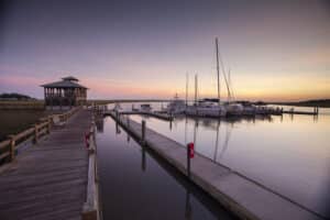A long pier, boathouse and boats docked at Delegal Creek Marina at sunrise.