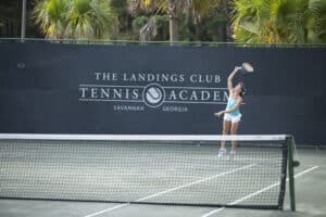 A young woman serves the ball on one of the tennis courts at The Landings Club Tennis Academy.