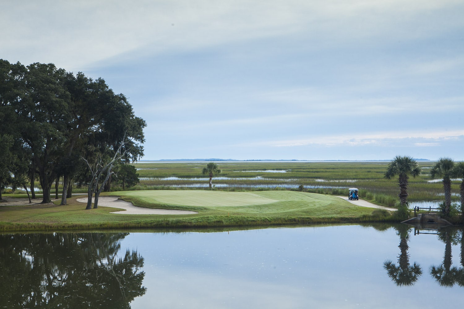 A calm lagoon lies in front of a golf course green at The Landings.