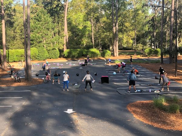 A fitness class takes place in an outdoor parking lot during COVID-19.
