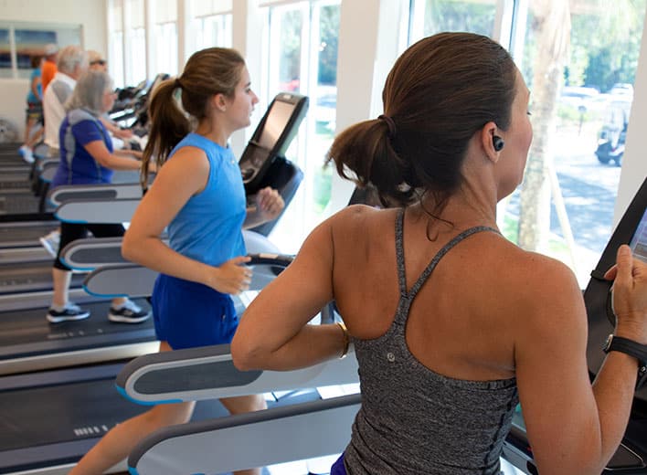 Two women in workout apparel run on adjacent treadmills at the Oakridge Wellness Center.