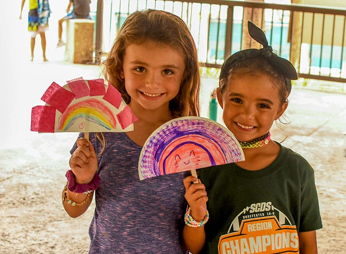 Two young girls show off the artwork they made during one of the youth summer camps.