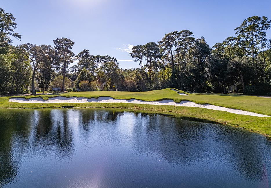 Water hazard flanked by sand traps with trees in the background on the Magnolia golf course designed by pro Arnold Palmer.