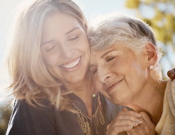 A smiling daughter hugs close her aging mother at a post-retirement, assisted living community on Skidaway Island.