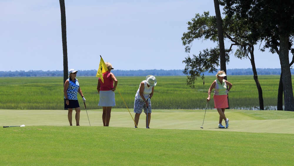 Four women on one of the golf course greens living the golf life at The Landings.