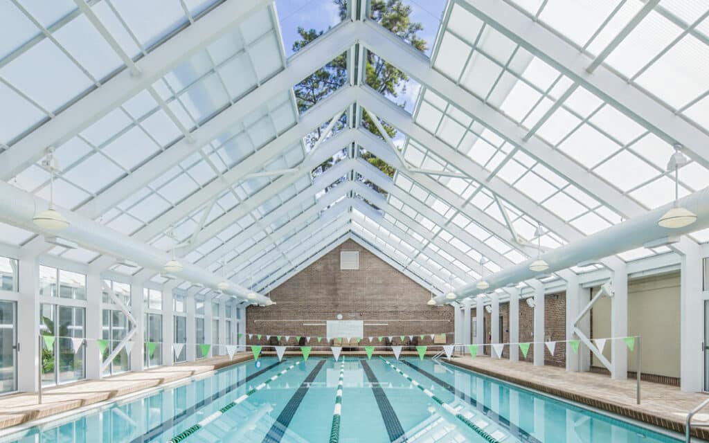A long lap pool at the Oakridge Wellness Center is enclosed by an all-glass vaulted ceiling.