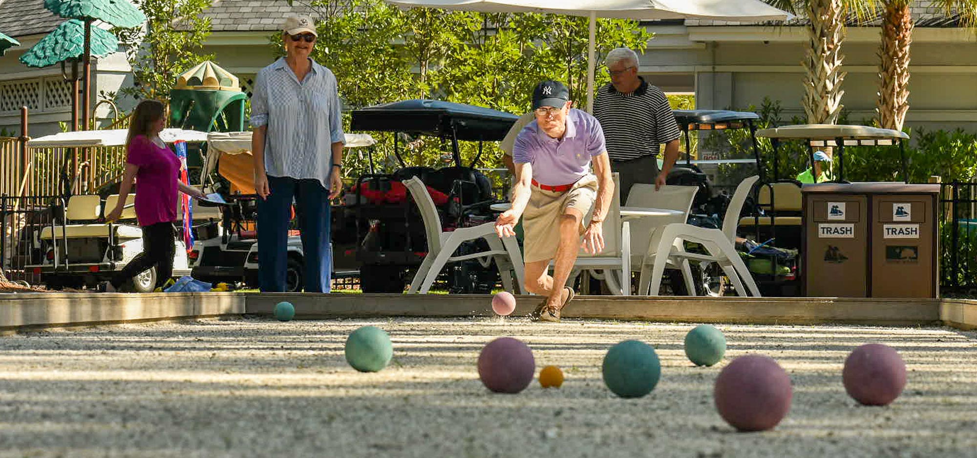 A man wearing a ball cap crouches as he rolls a bocce ball across one of the eight courts at the Franklin Creek Sports Complex.