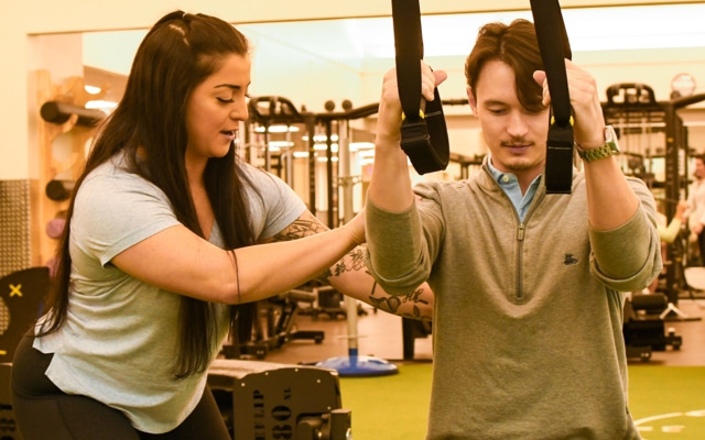 A female fitness instructor works with a young man during a personal training session at Oakridge Wellness Center.