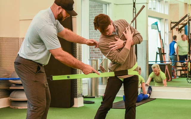 A male trainer works with a man on his golf swing during one of the specialty training programs offered at Oakridge Wellness Center.