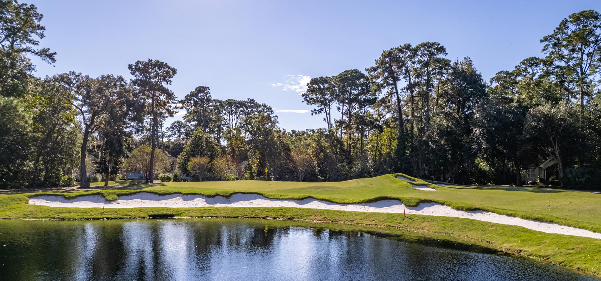The Magnolia course offers a water obstacle that lies in front of a long narrow sand trap with the green's pin nestled in the background.