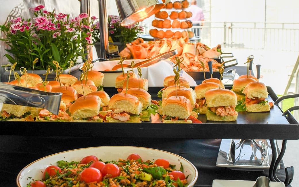 Sandwiches on a serving card with salad in the foreground are prepared for a recent catering event.