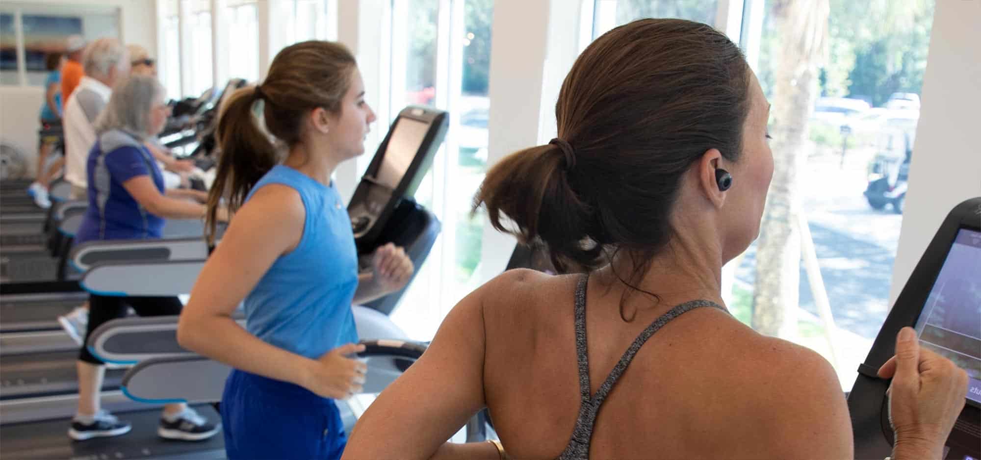 Two women in workout apparel run on adjacent treadmills at the Oakridge Wellness Center.