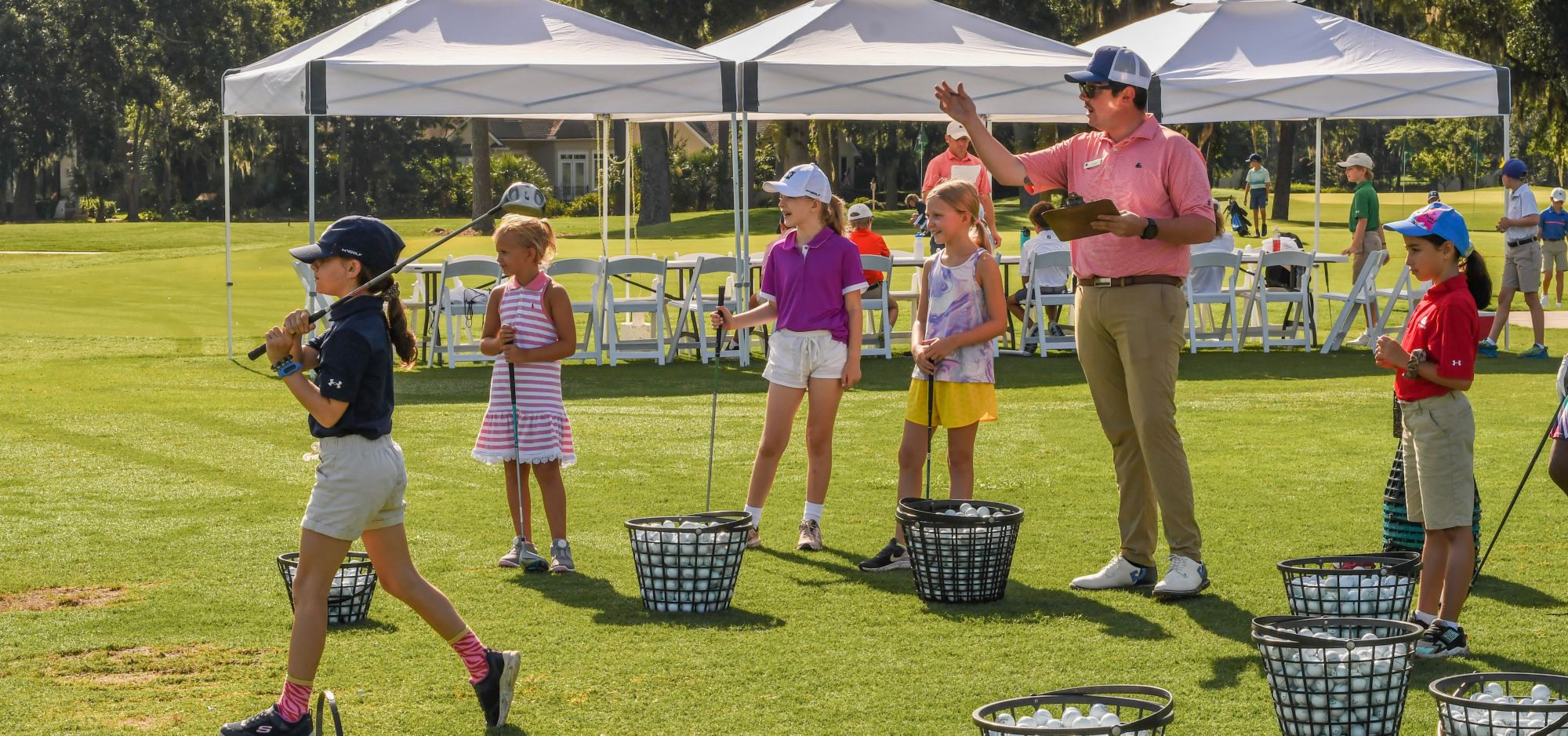 A golf instructor teaches kids at The Landings Golf & Athletic Club